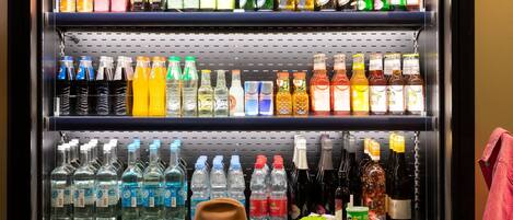 Un refrigerador de bebidas repleto de diversas opciones, como gaseosas, jugos y bebidas alcohólicas.