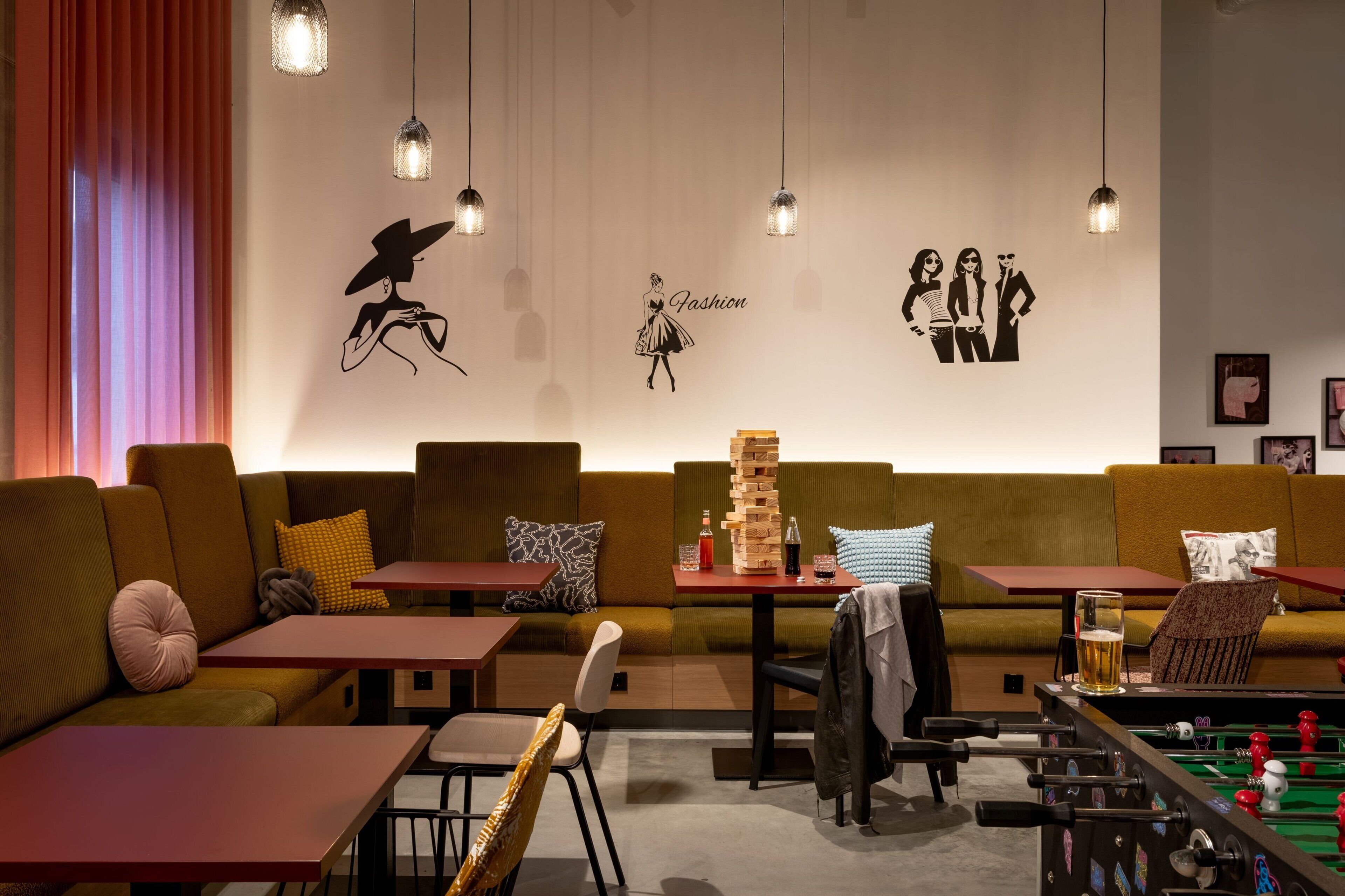 Un espacio lounge acogedor con sofás, mesas y una mesa de futbolín.