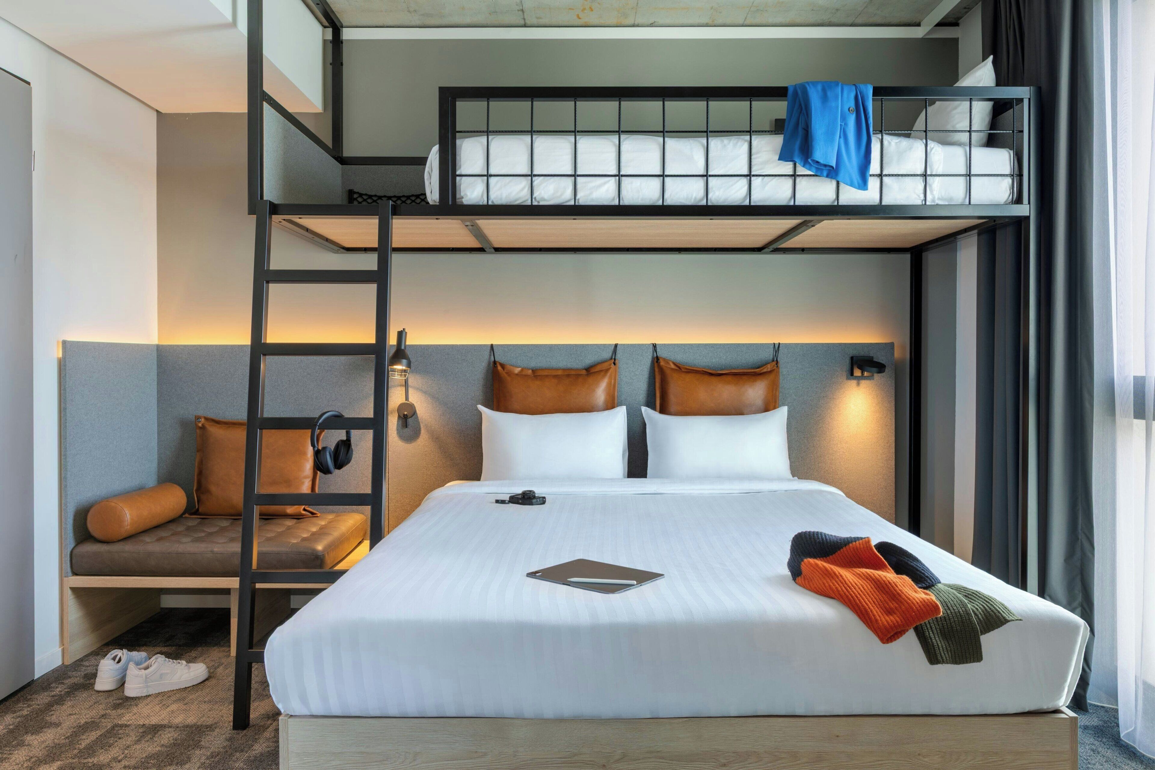 A bunk bed room with a desk, a chair, and a laptop.