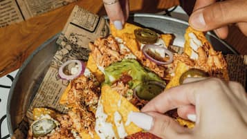 A person holding a tortilla chip with a meal.
