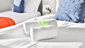 A neatly made bed with white linens, a blue pillow, and a red blanket. - Spacious 3 Bedroom House in Barry (Barry)
