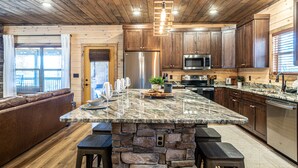 Una cocina moderna con una isla de piedra, armarios de madera y electrodomésticos de acero inoxidable.