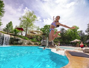 Ein Poolbereich mit Wasserrutsche, Wasserfall und Sprungbrett.