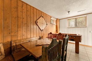 A room with a wooden table set for dining, a foosball table, and a dartboard on the wall. - Spacious Resort Cabin – Sleeps 16, Minutes to Silver Dollar City! (Branson)
