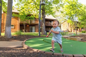 A child playing on artificial turf with a building in the background.