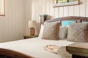 Ein Bett mit Holz-Kopfteil, ein Nachttisch mit Lampe und dekorative Kissen.