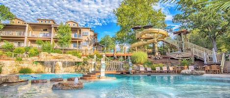 A resort with a pool, a water slide, and a view of the surrounding buildings.