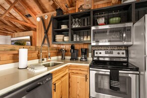 A modern kitchen with wooden cabinetry, stainless steel appliances, and a built-in oven. - Spacious Resort Cabin – Sleeps 16, Minutes to Silver Dollar City! (Branson)