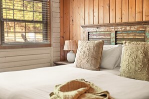 A bedroom with a wooden headboard, a bed with white linens, and decorative pillows.