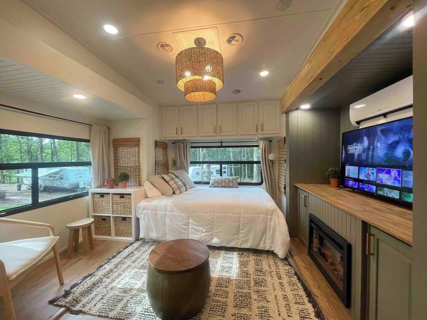 A modern bedroom with a large bed, a television, and a view of the outdoors.