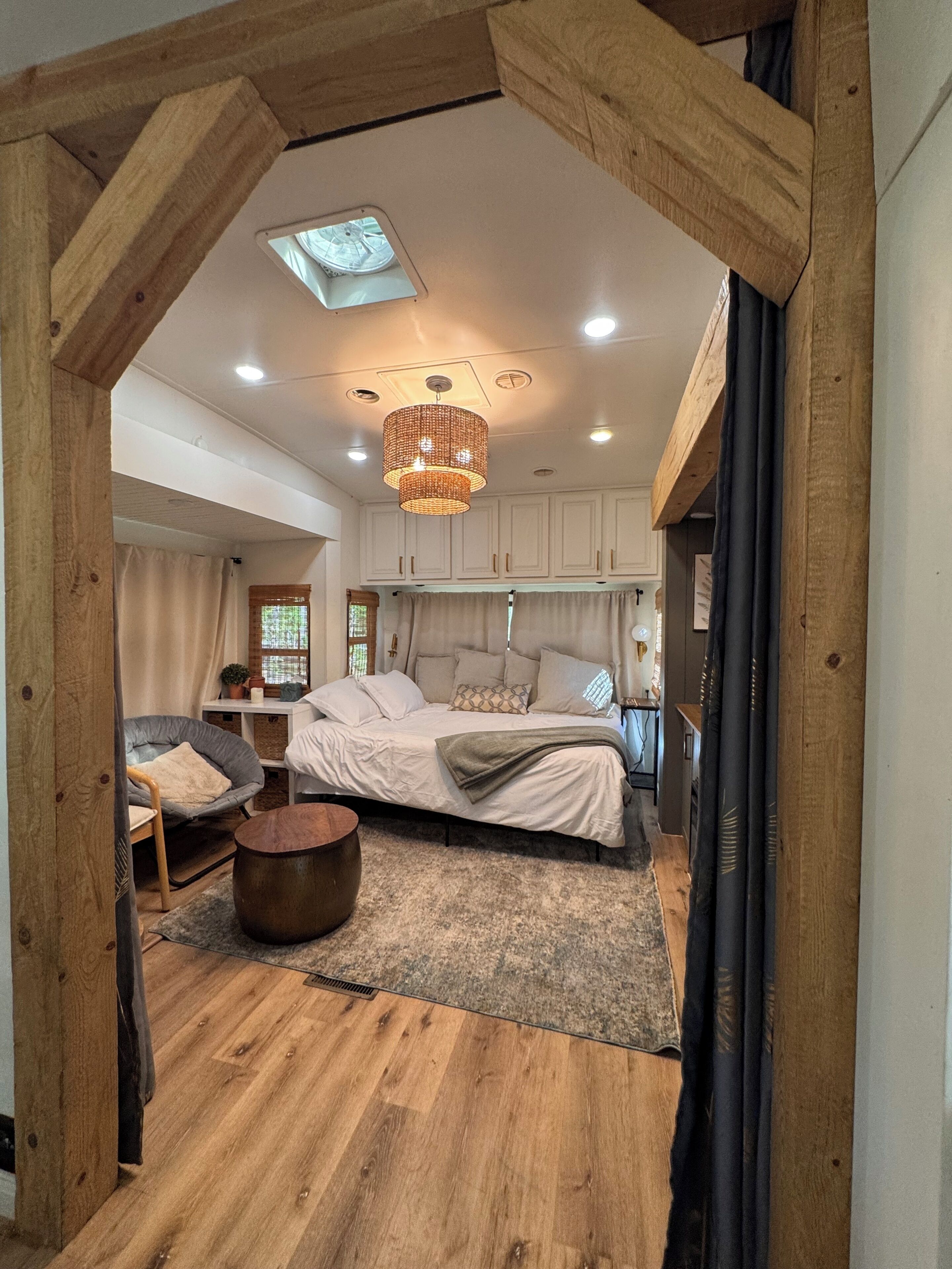 Ein Schlafzimmer mit einem Bett, einem runden Holztisch, einem Stuhl und einem Dachfenster.