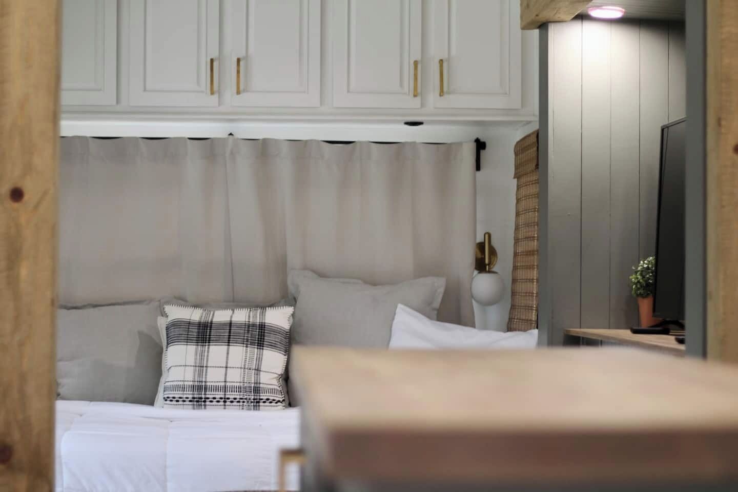 Une chambre à coucher avec un lit, des rideaux blancs, une lampe de chevet et un miroir.