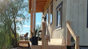 Une terrasse en bois avec un escalier menant à un porche abrité.