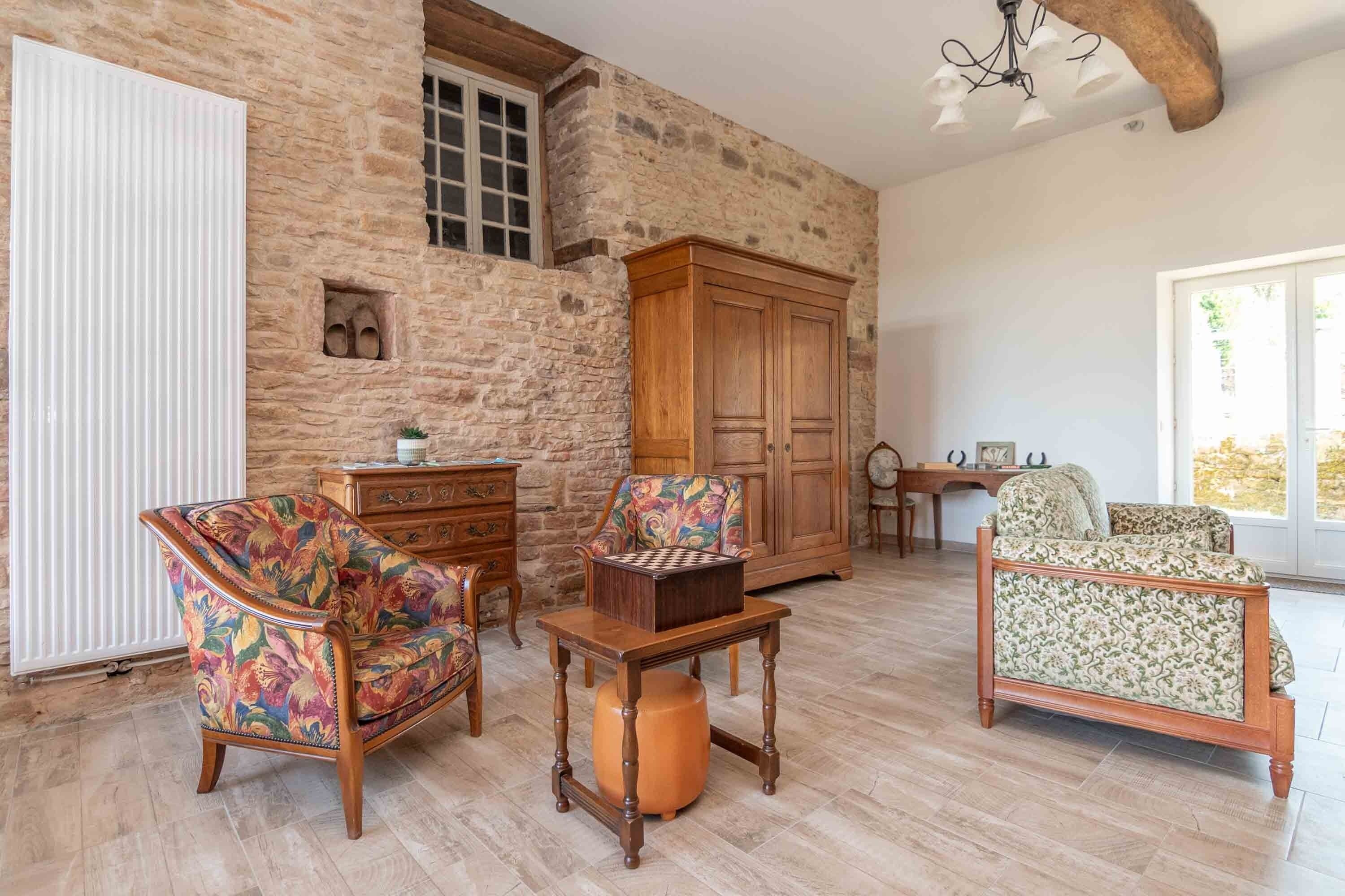 Une pièce avec un mur en pierre, des meubles en bois et une grande fenêtre.