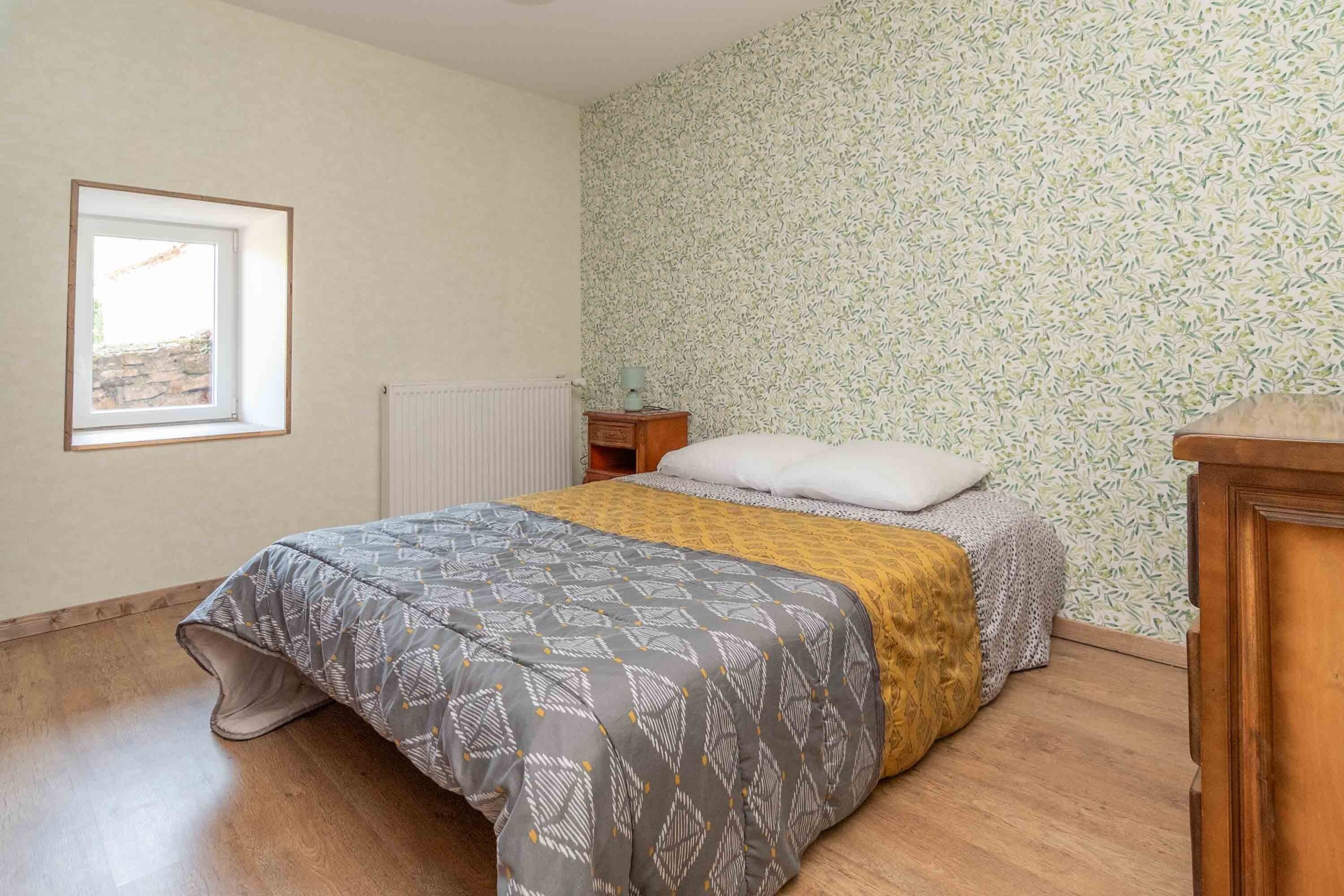Ein Schlafzimmer mit einem Bett, einem Nachttisch, einem Heizkörper und einem Fenster.