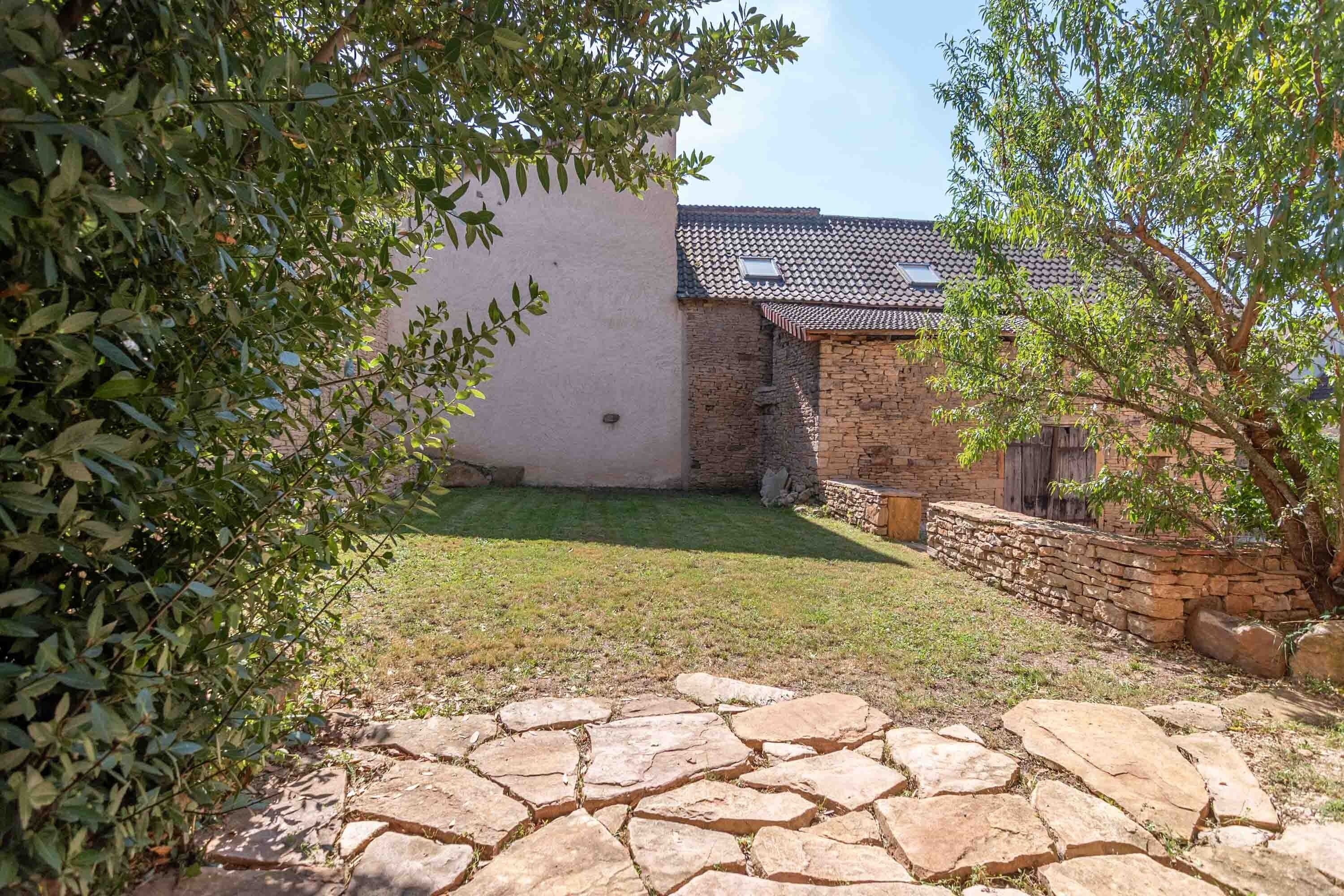 A courtyard with stone paving, a grassy area, and a building with a tiled roof.