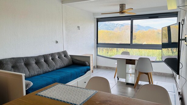 Een moderne kamer met een bank, een eettafel en uitzicht op bergen door grote ramen.