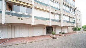 Een meerlaags woongebouw met een platte gevel, grote ramen en een entreegebied met rode tegels.