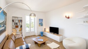 Un saló modern amb un sofà, una taula de centre i una televisió. Hi ha una prestatgeria i un quadre a la paret.