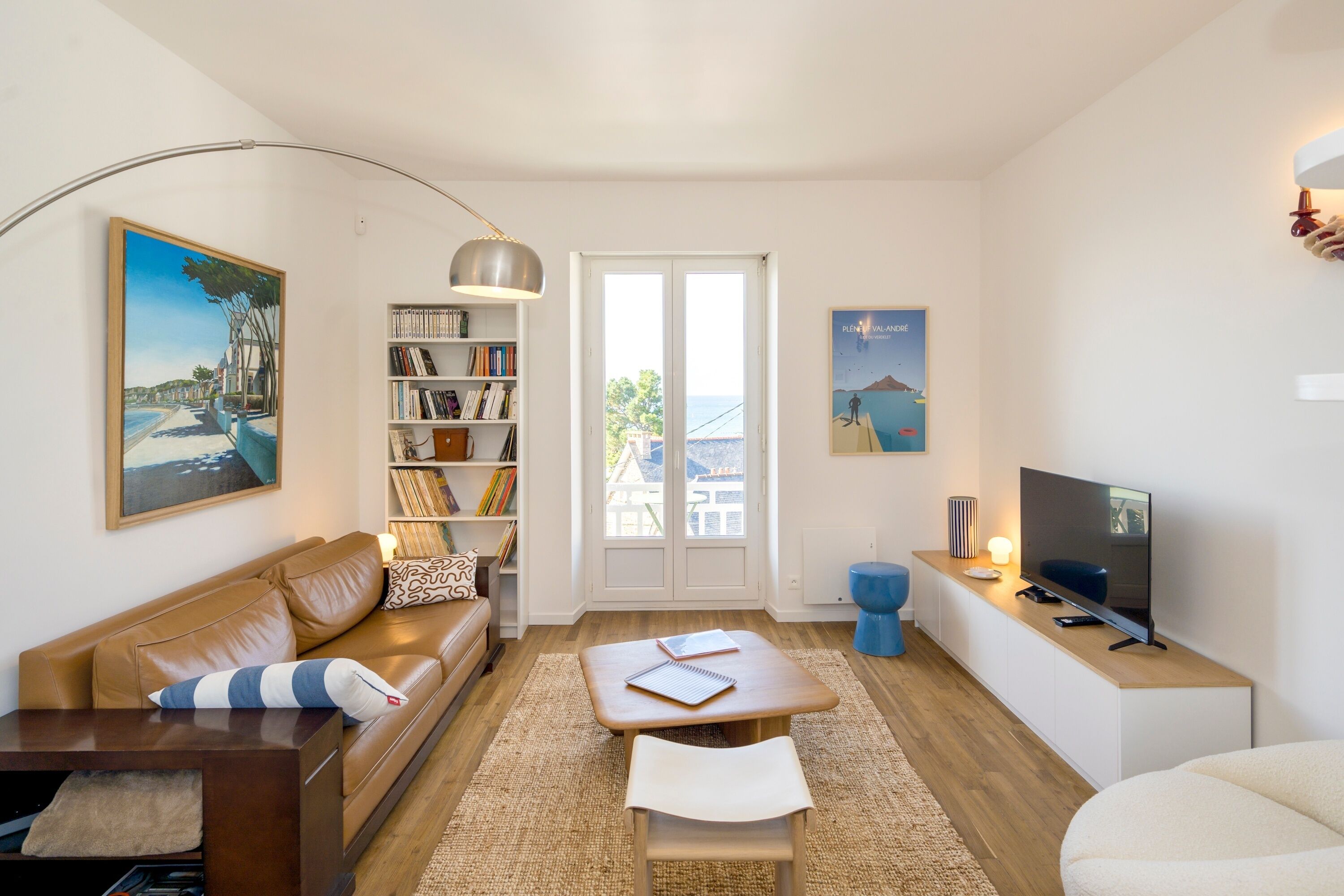 A modern living room with a sofa, coffee table, bookshelf, and a television.