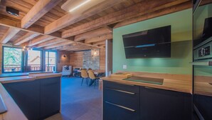A modern kitchen with wooden beams, a flat-screen TV, and a stone accent wall.