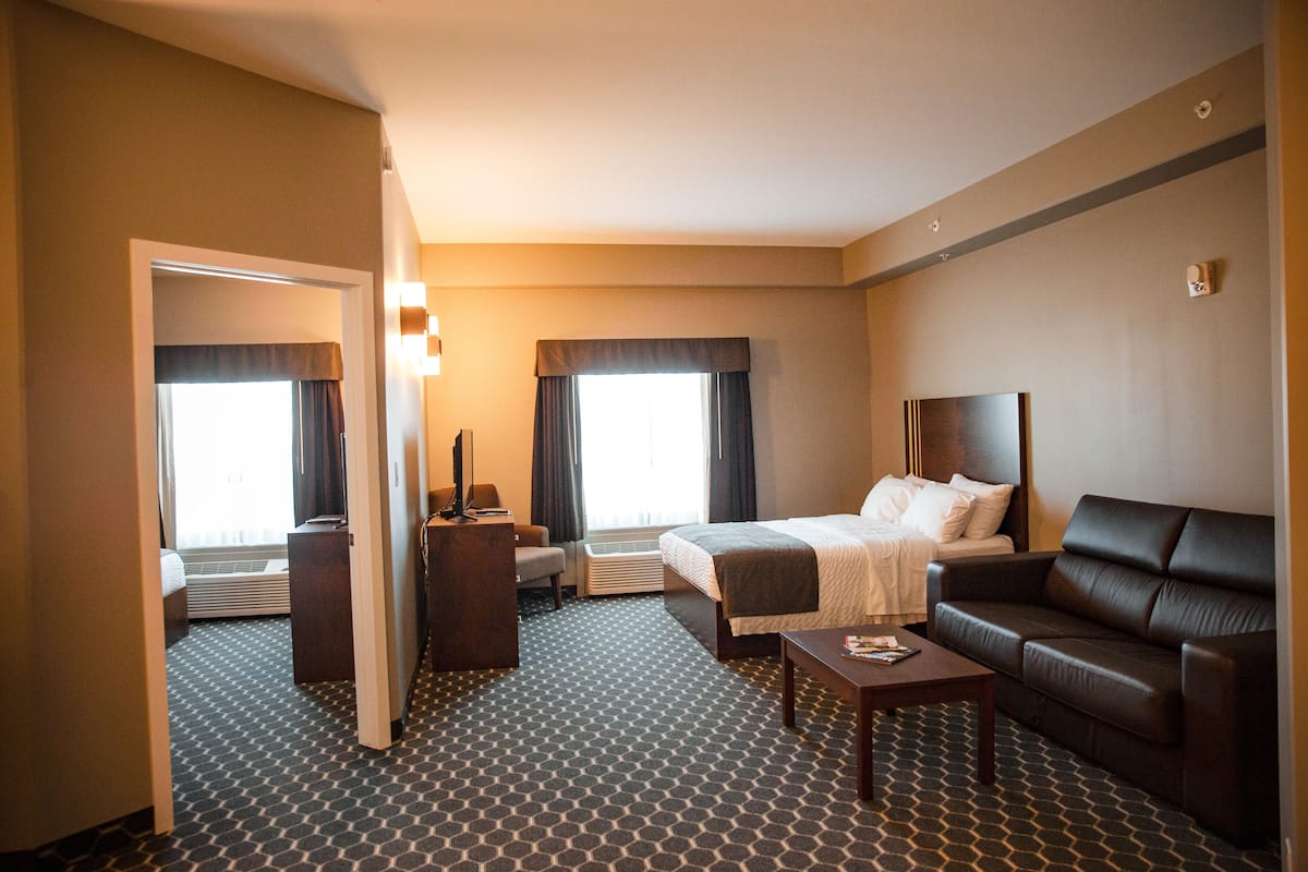 Una habitación de hotel con cama, sofá, escritorio y una silla.