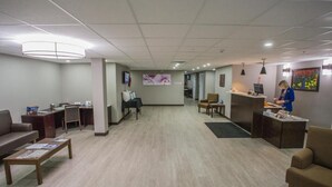 Un vestíbulo amplio con mostrador de recepción, zona de estar y una oficina visible al fondo.