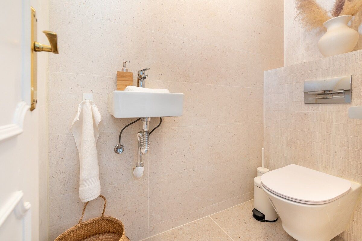 Une salle de bain avec un lavabo blanc, des toilettes et une serviette accrochée au mur.