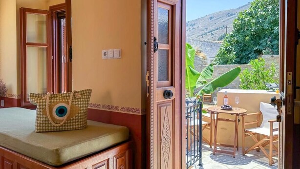 A room with a wooden cabinet, a bench with cushions, and a view of a patio with a table and chairs.