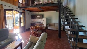 Amplia sala de estar con mesa de comedor, sofá y una escalera que lleva a un nivel superior.