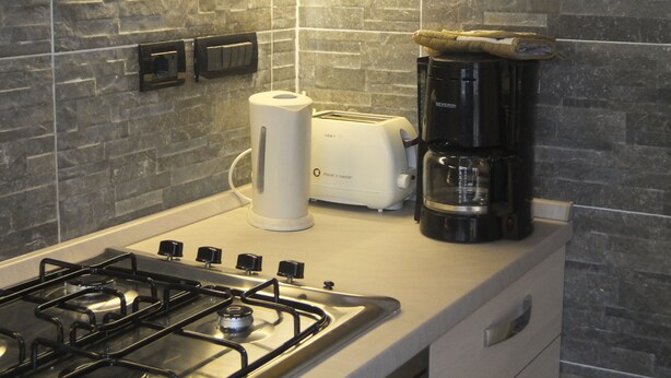 Een keuken met een gasfornuis, een broodrooster en een koffiezetapparaat op het aanrecht.