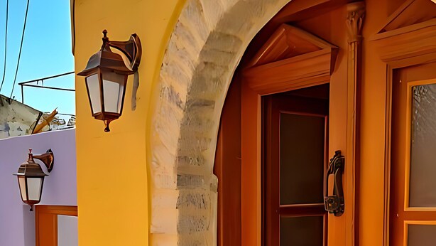 Un edificio amarillo con una puerta de madera y dos faroles en la pared.