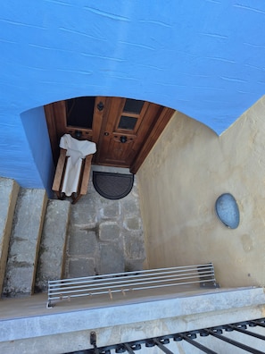 A stone staircase leading to a wooden door with a window, a metal handrail, and a blue awning. - Symi Uptown Indigo Street View Studio (Symi, Dodecanese)