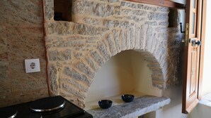 Una cocina con chimenea de arco de piedra, estufa y dos cuencos en una repisa.