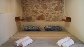 Una habitación pequeña con paredes de piedra, dos almohadas y dos toallas enrolladas en el suelo.