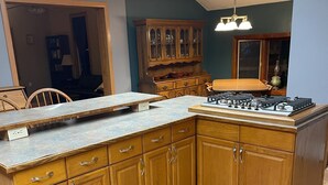 A kitchen with wooden cabinets, a countertop, and a gas stove. - Quiet farmhouse with amazing views - close to skiing in Ellicotville! (Little Valley)