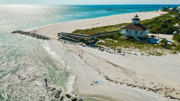 Una zona costera con un muelle, un faro y una playa.