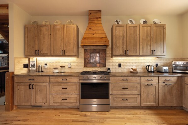 Una cocina con armarios de madera, una estufa central y un salpicadero de ladrillo.