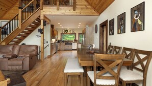 Un vaste espace de vie agrémenté d’un escalier en bois, d’une table à manger et d’une cuisine située au fond de la pièce.