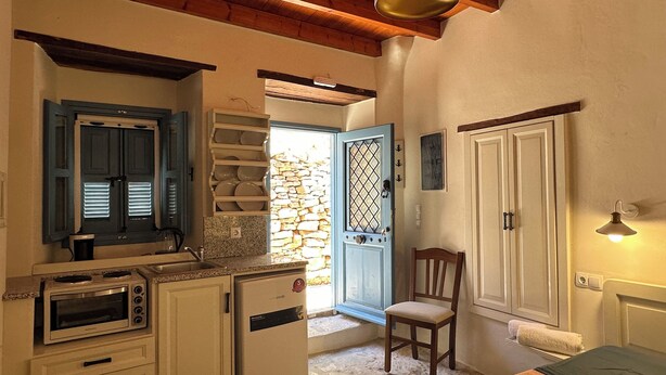 Una cocina compacta con horno empotrado, un refrigerador pequeño y una pared de piedra.
