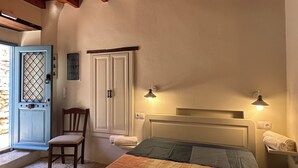 Un dormitorio con cama, una silla, armario y puerta.