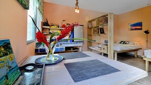 Ein gemütliches Zimmer mit Esstisch, Bett, Küchenzeile und Bücherregal.