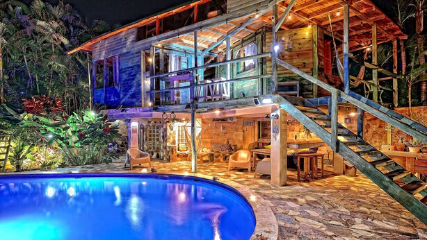 Ein mehrgeschossiges Holzhaus mit Swimmingpool, Sitzgelegenheit im Freien und einer Treppe.