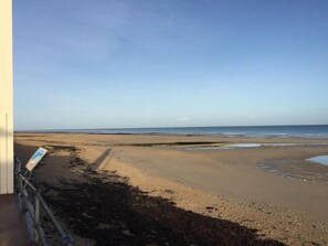 Ein Strand mit blauem Himmel, sandigem Ufer und einem Schild links.