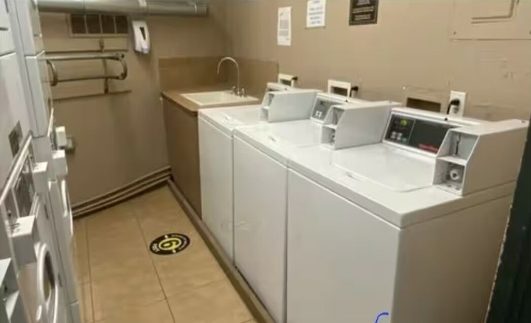 A compact laundry facility with multiple washing machines and a sink.