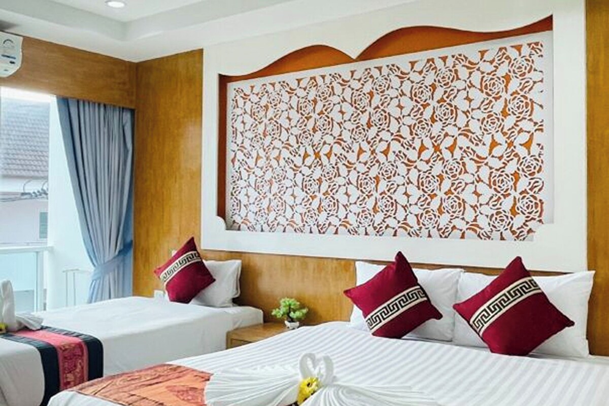A hotel room with two beds, a decorative wall panel, and a window with curtains.
