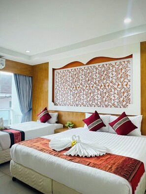 A hotel room with two beds, a decorative wall panel, and a window with curtains. - T & C Hotel Patong Beach By Zuzu (Patong)