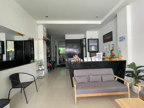 A modern hotel lobby with a grey sofa, a black reception desk, and a mirror. - T & C Hotel Patong Beach By Zuzu (Patong)