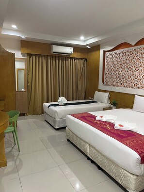 A hotel room with two beds, a desk, a chair, and an air conditioning unit. - T & C Hotel Patong Beach By Zuzu (Patong)