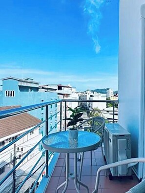 A balcony with a round table and chairs, a potted plant, and an air conditioning unit. - T & C Hotel Patong Beach By Zuzu (Patong)